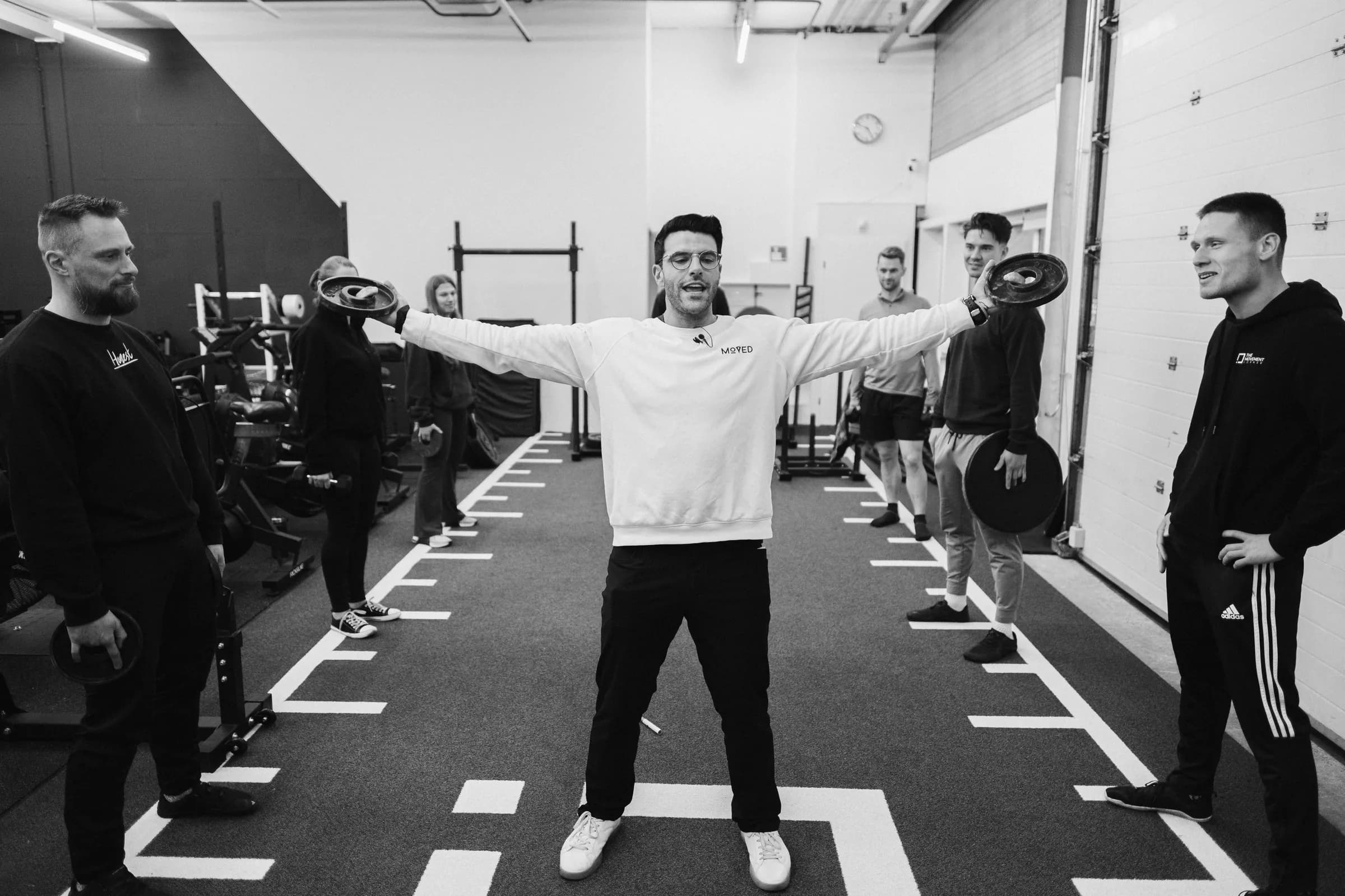 Richard Aceves standing arms outstretched, coaches mirroring the position around him