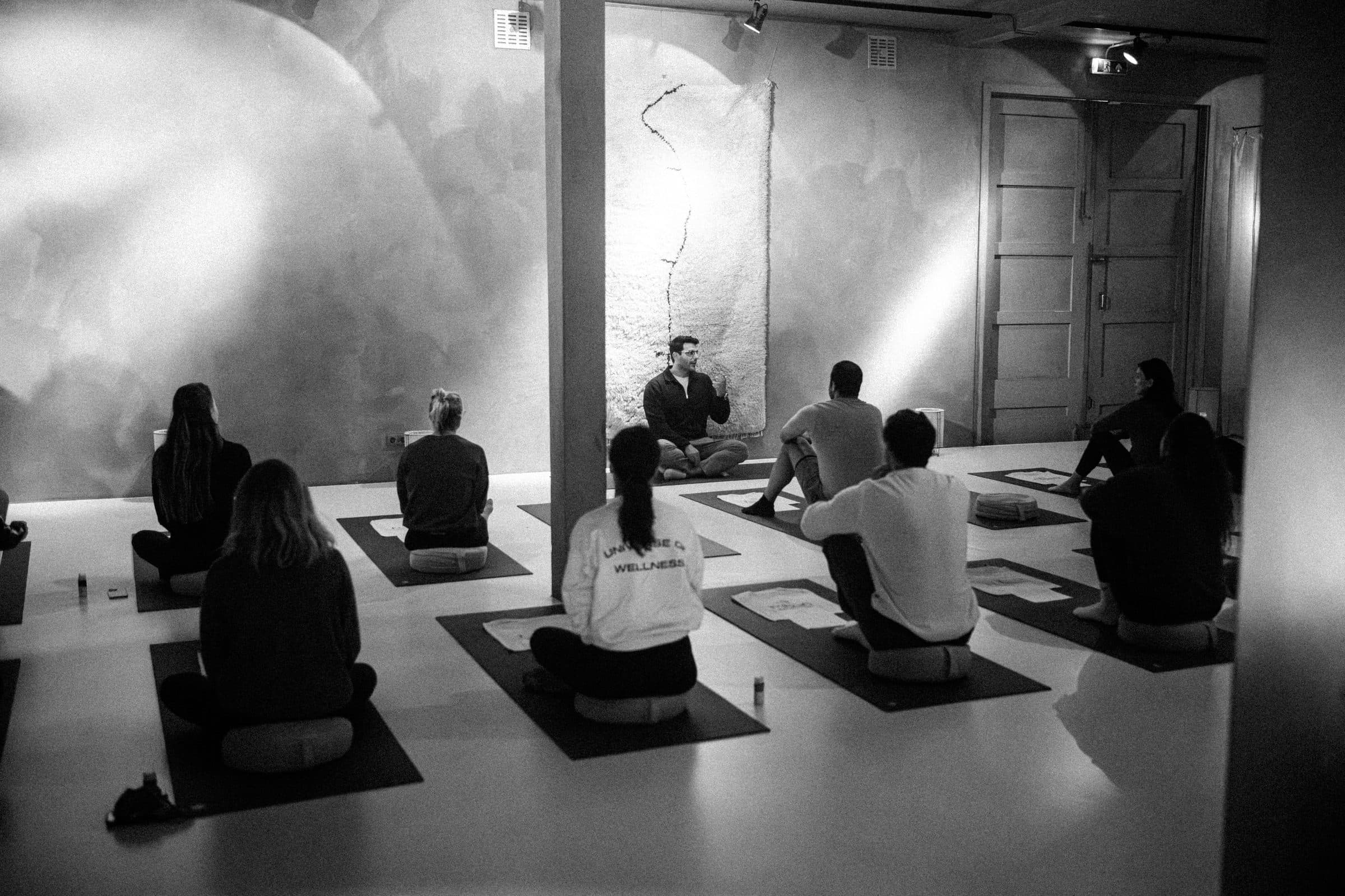 A seated circle of participants facing Richard Aceves in a dimly lit room