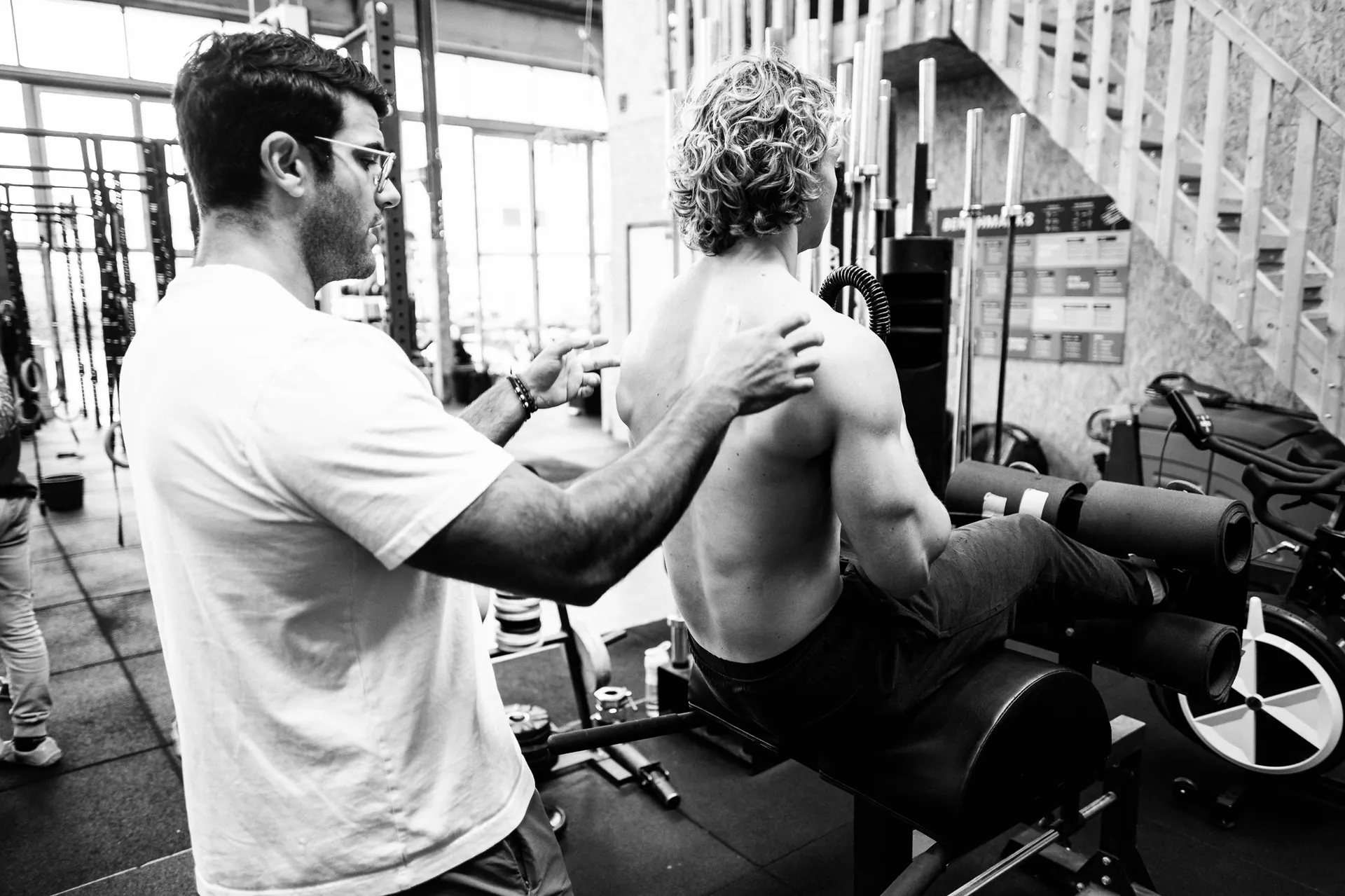 Richard Aceves placing a hand on a client's back to correct posture during a gym assessment