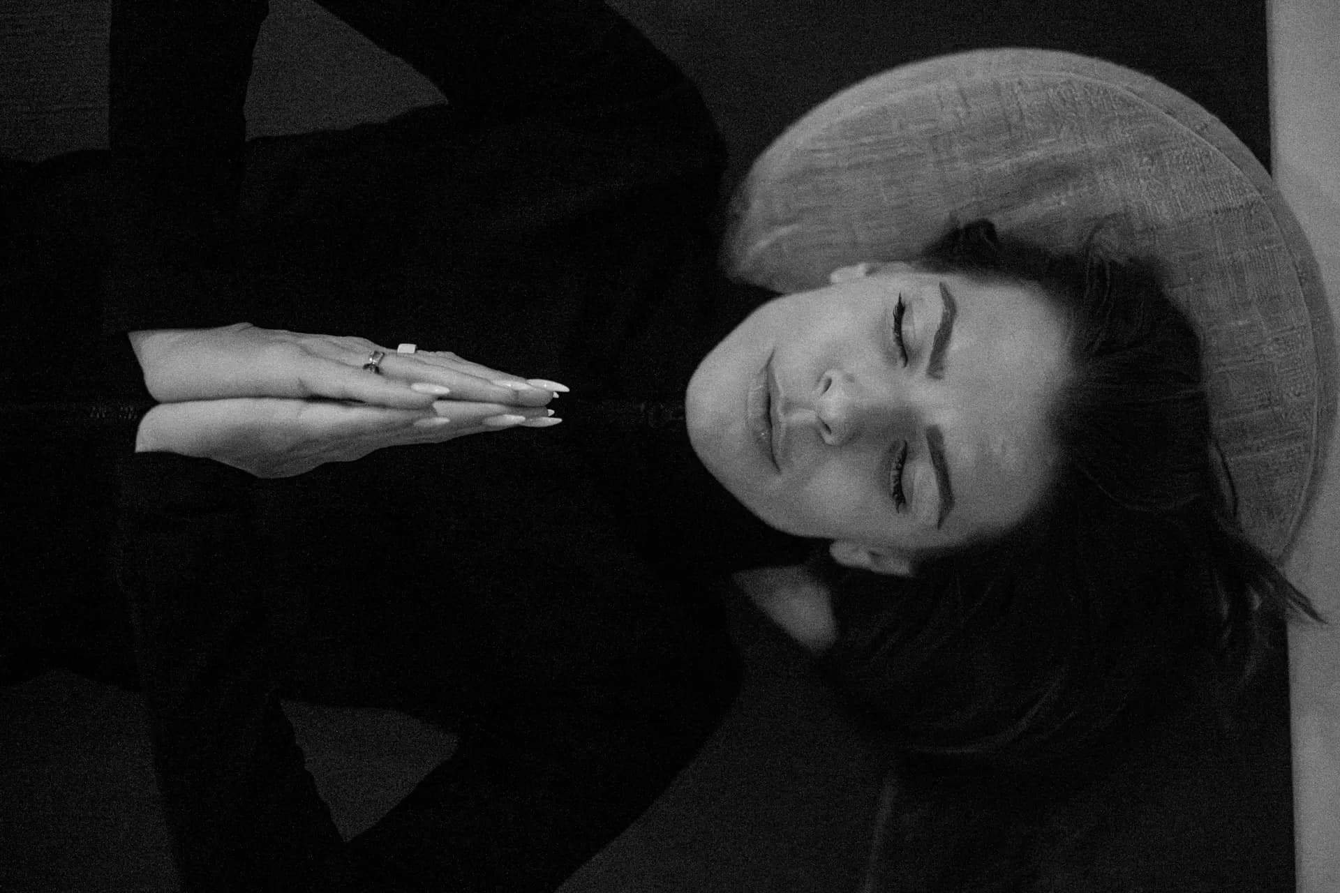 A person lying on a mat with eyes closed and hands resting over the chest