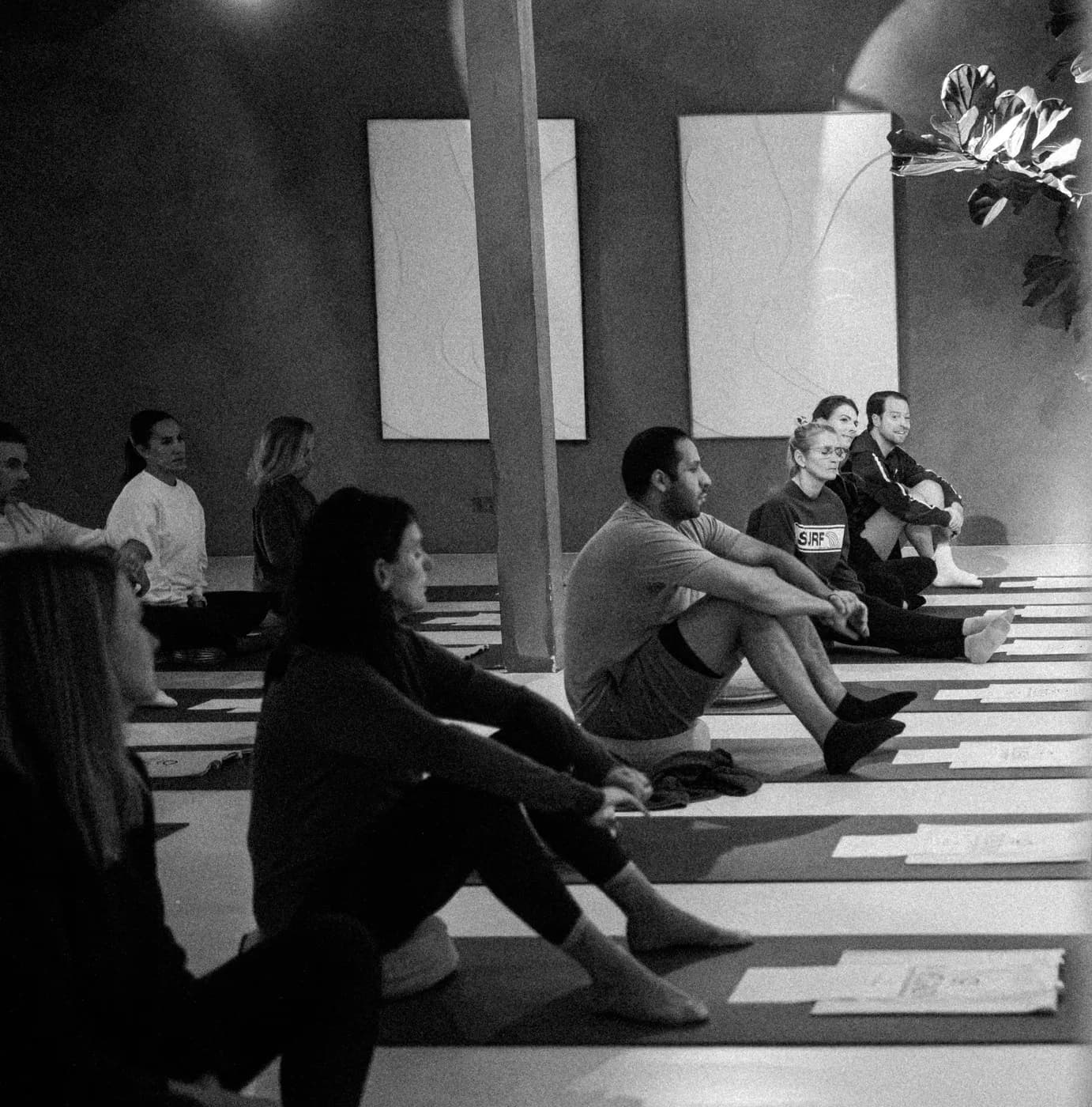 A group seated on mats in a bright studio during a Swami practice
