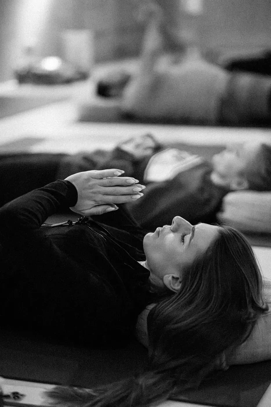 A person lying on a mat with one hand on the chest during a guided Swami practice